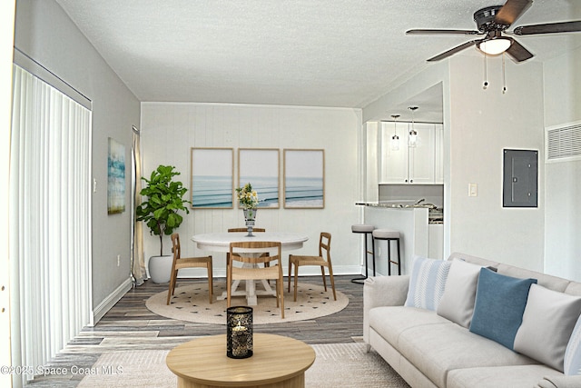 living room featuring hardwood / wood-style floors, a textured ceiling, electric panel, and ceiling fan