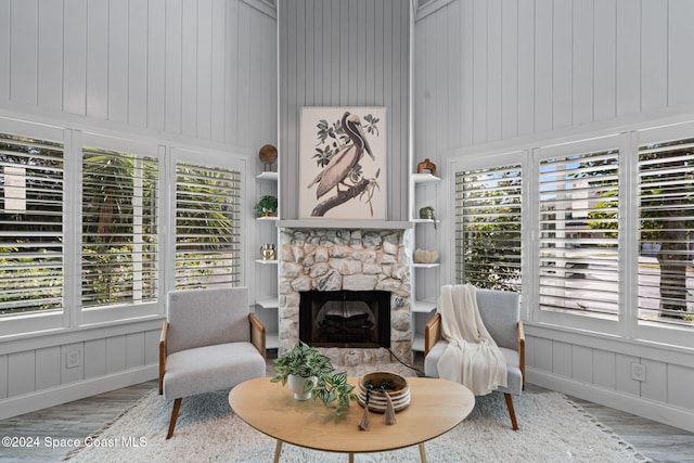 sitting room featuring a stone fireplace, plenty of natural light, and light hardwood / wood-style floors