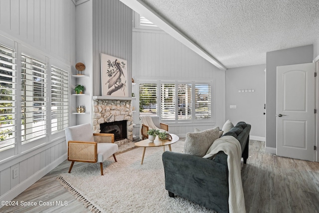 living room featuring a textured ceiling, a stone fireplace, hardwood / wood-style floors, and plenty of natural light