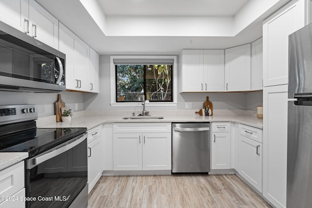 kitchen featuring white cabinetry, sink, light wood-type flooring, and appliances with stainless steel finishes