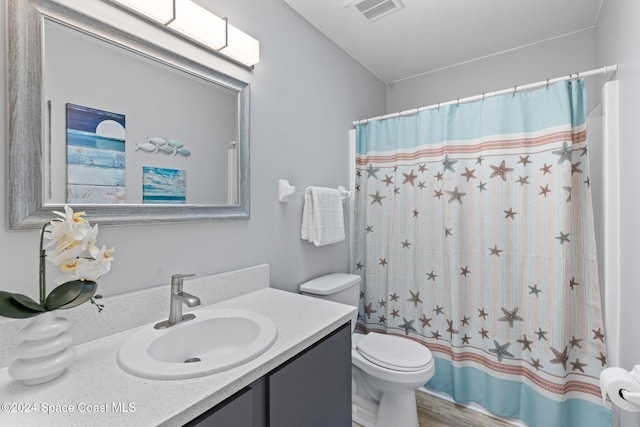 bathroom with walk in shower, hardwood / wood-style floors, vanity, and toilet