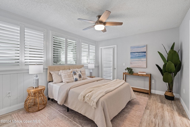 bedroom with ceiling fan, light hardwood / wood-style floors, and a textured ceiling