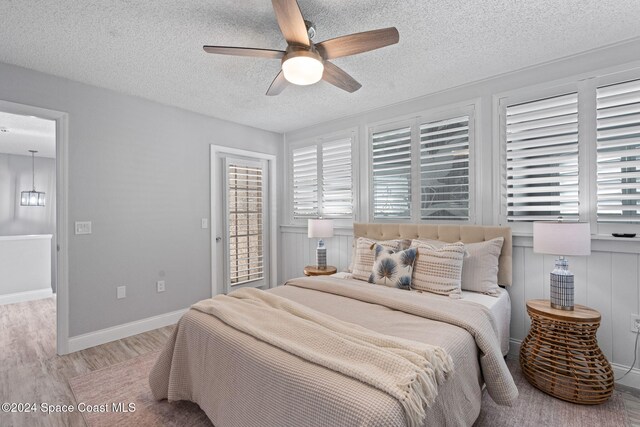 bedroom featuring ceiling fan, light hardwood / wood-style floors, a textured ceiling, and multiple windows