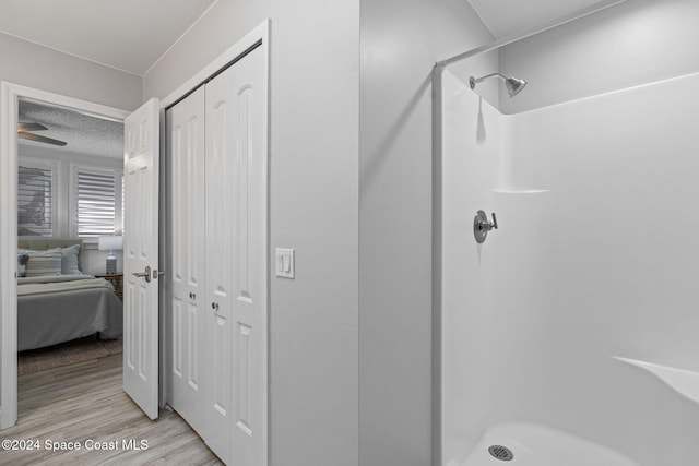 bathroom with hardwood / wood-style flooring, walk in shower, and a textured ceiling