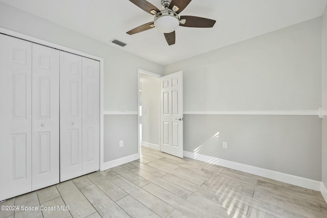 unfurnished bedroom featuring ceiling fan, a closet, and light wood-type flooring