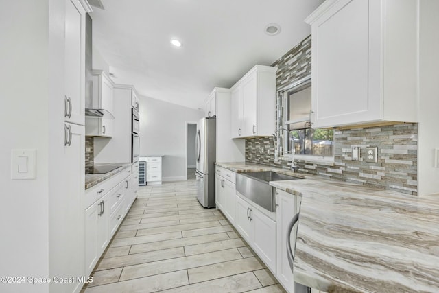 kitchen with light stone countertops, white cabinetry, sink, and stainless steel appliances