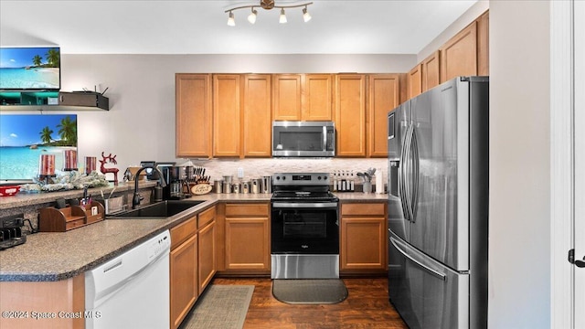 kitchen with dark stone counters, sink, dark hardwood / wood-style floors, decorative backsplash, and stainless steel appliances