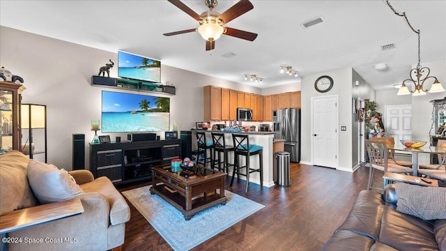 living room featuring ceiling fan with notable chandelier and dark wood-type flooring