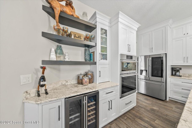 kitchen with white cabinets, appliances with stainless steel finishes, dark hardwood / wood-style flooring, and a textured ceiling