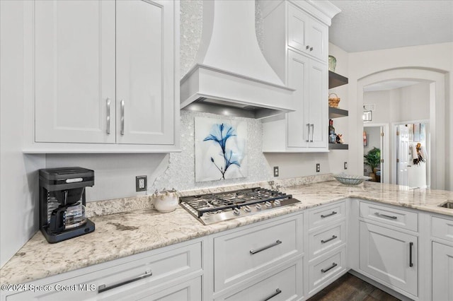 kitchen featuring light stone countertops, premium range hood, white cabinets, dark hardwood / wood-style floors, and stainless steel gas stovetop