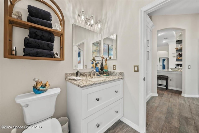 bathroom featuring wood-type flooring, vanity, and toilet