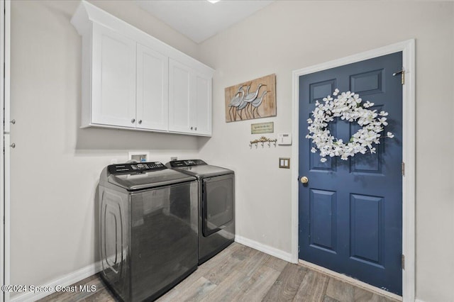 clothes washing area featuring washer and dryer, hardwood / wood-style flooring, and cabinets