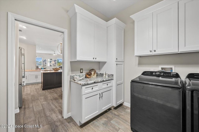 washroom featuring cabinets, hardwood / wood-style floors, and washing machine and dryer