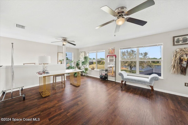 living area with ceiling fan, dark wood-type flooring, and a healthy amount of sunlight