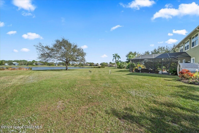 view of yard with a lanai and a water view