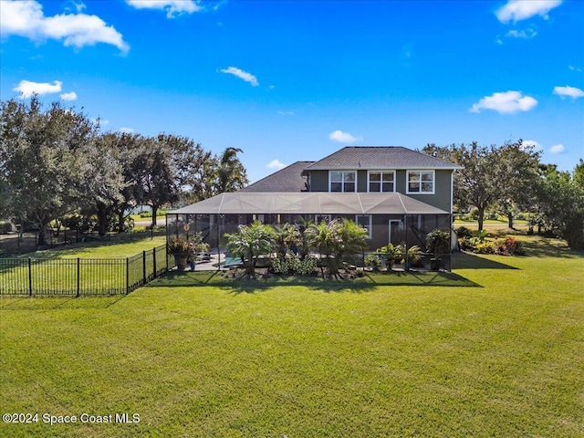 rear view of house with a lanai and a yard