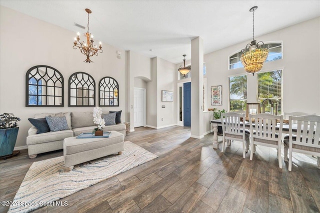 living room with a high ceiling, dark wood-type flooring, and a notable chandelier