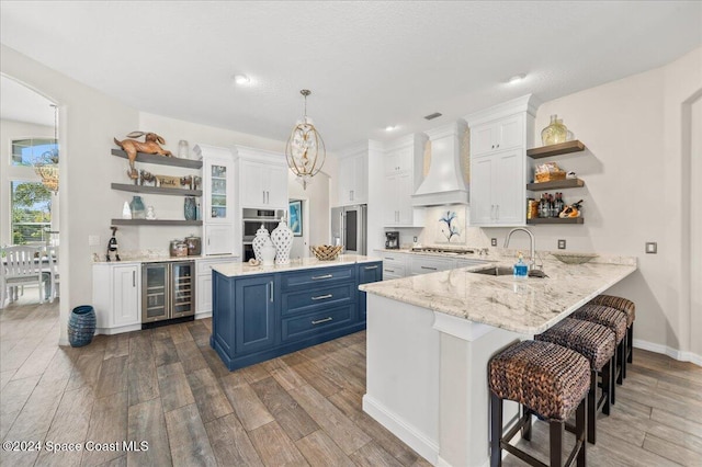 kitchen featuring sink, white cabinets, custom range hood, and blue cabinets