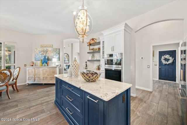 kitchen featuring blue cabinetry, stainless steel double oven, hardwood / wood-style floors, pendant lighting, and white cabinets