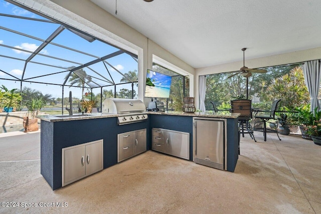 view of patio / terrace with an outdoor kitchen, a wet bar, a lanai, and a grill