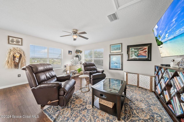 living room with ceiling fan, a healthy amount of sunlight, dark hardwood / wood-style flooring, and a textured ceiling