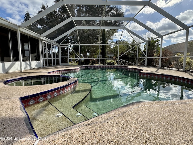 view of swimming pool with an in ground hot tub, a patio, and a lanai