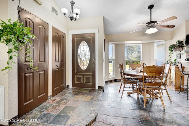 foyer with a textured ceiling and ceiling fan with notable chandelier