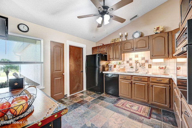 kitchen featuring lofted ceiling, backsplash, black appliances, sink, and tile counters