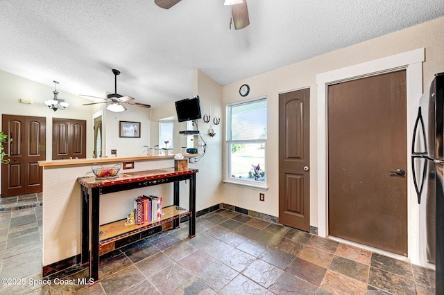 kitchen with refrigerator, lofted ceiling, and a textured ceiling