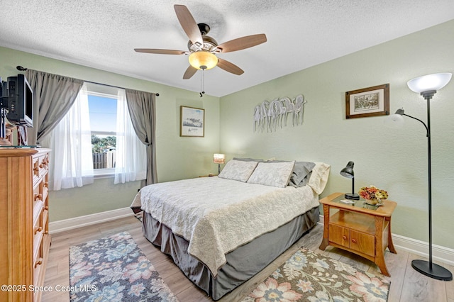 bedroom with ceiling fan, a textured ceiling, and light wood-type flooring