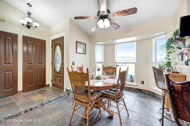 dining area with a textured ceiling, ceiling fan with notable chandelier, and lofted ceiling