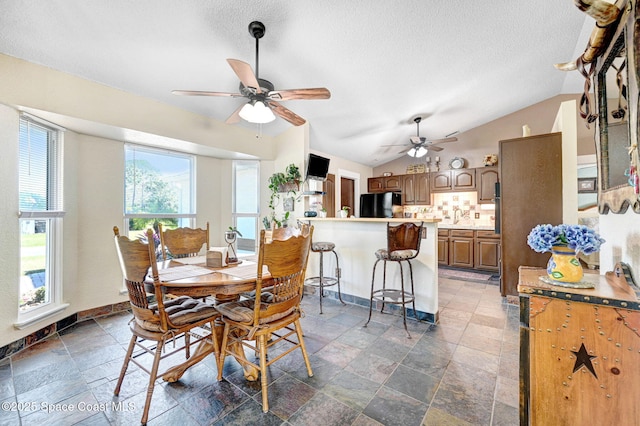 dining area featuring a textured ceiling, ceiling fan, lofted ceiling, and sink