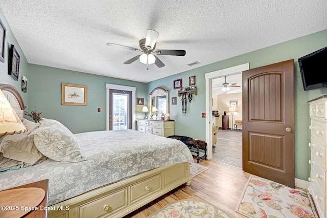 bedroom featuring ceiling fan, light hardwood / wood-style floors, and a textured ceiling