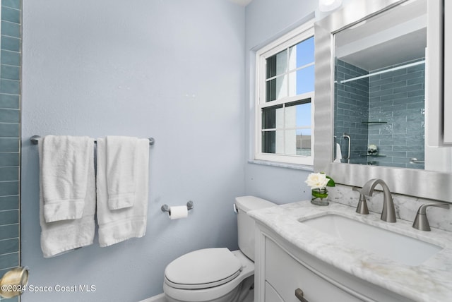 bathroom featuring tiled shower, vanity, and toilet