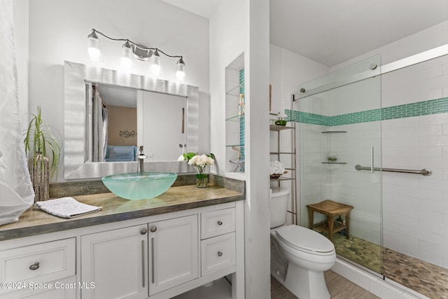 bathroom with hardwood / wood-style flooring, toilet, vanity, and walk in shower