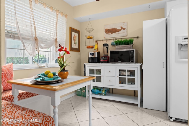 kitchen with light tile patterned floors and white refrigerator with ice dispenser