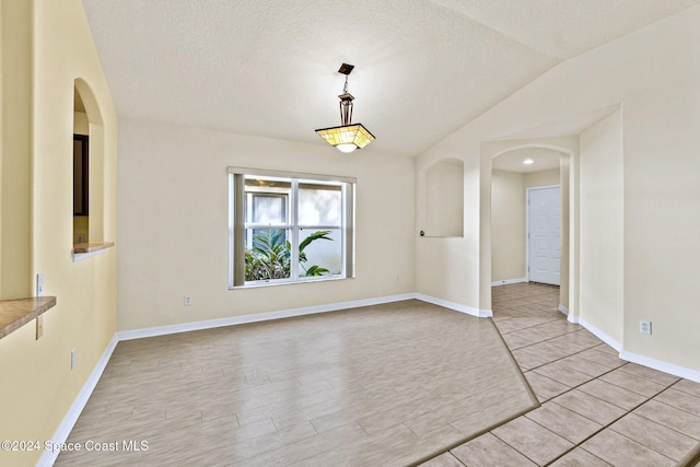 empty room with vaulted ceiling and a textured ceiling