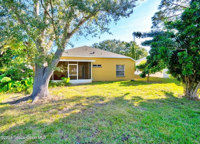 back of property with a sunroom and a yard