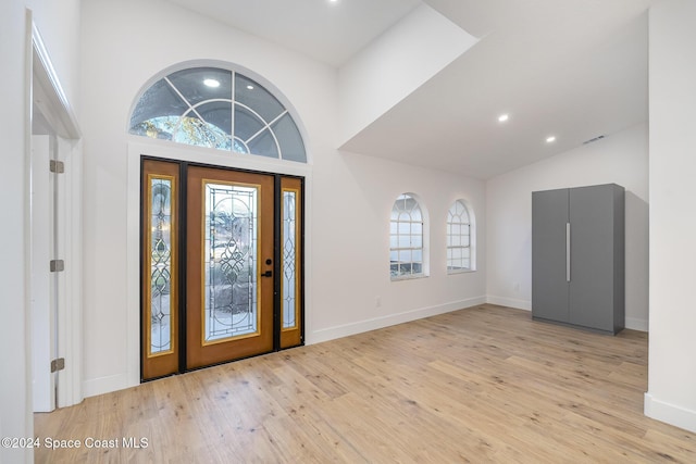 entryway featuring high vaulted ceiling, light wood-type flooring, and a wealth of natural light