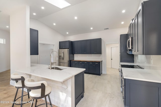 kitchen featuring a kitchen bar, kitchen peninsula, light stone countertops, and sink