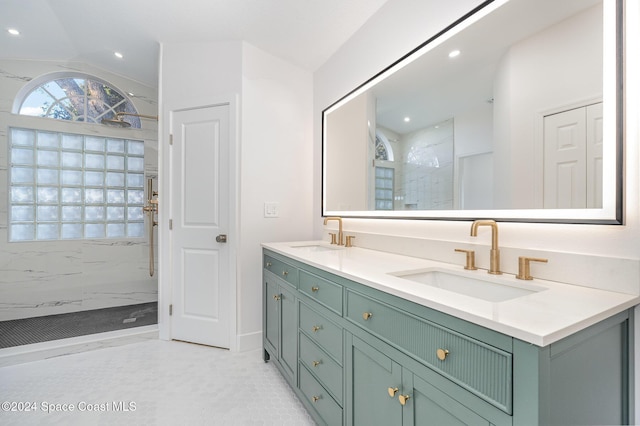 bathroom with tile patterned floors, vanity, a tile shower, and lofted ceiling