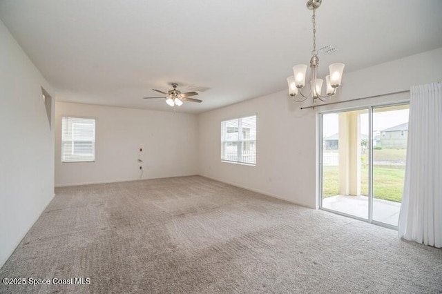 carpeted empty room featuring ceiling fan with notable chandelier