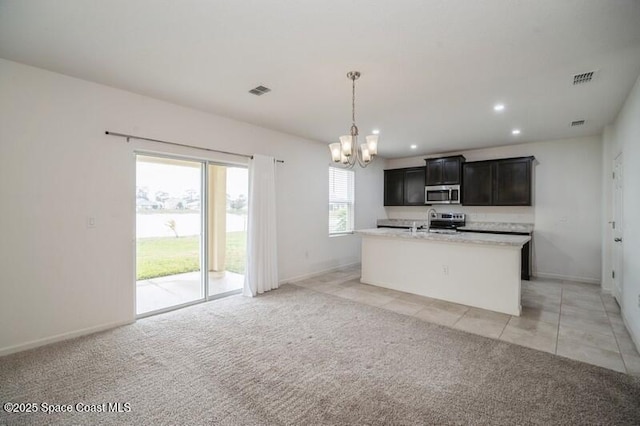 kitchen featuring stainless steel appliances, light colored carpet, decorative light fixtures, and a kitchen island with sink