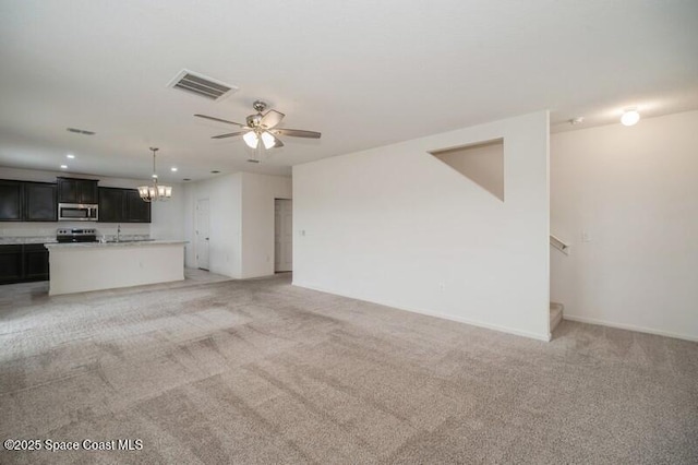 unfurnished living room featuring ceiling fan with notable chandelier and light colored carpet