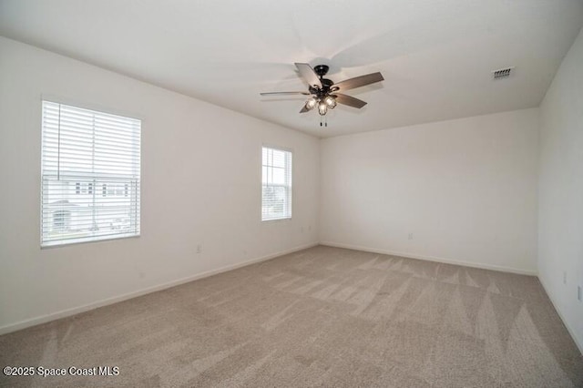 spare room with ceiling fan, light colored carpet, and plenty of natural light