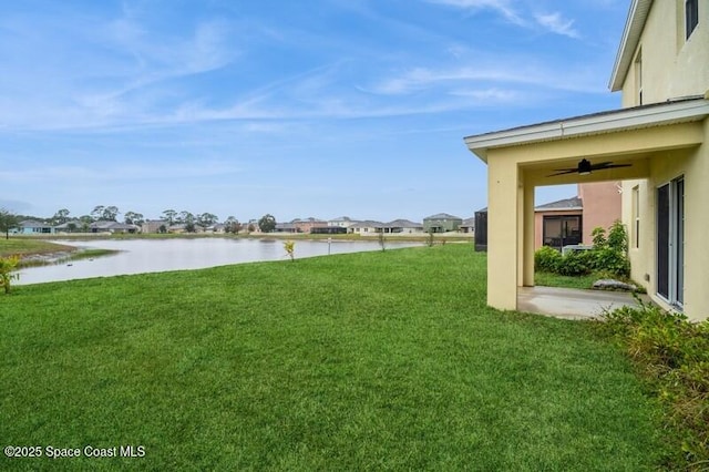 view of yard with ceiling fan and a water view