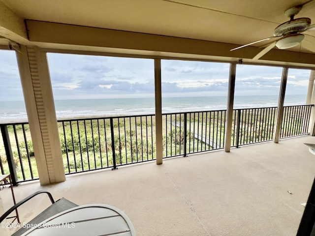 unfurnished sunroom with a beach view, a water view, and ceiling fan