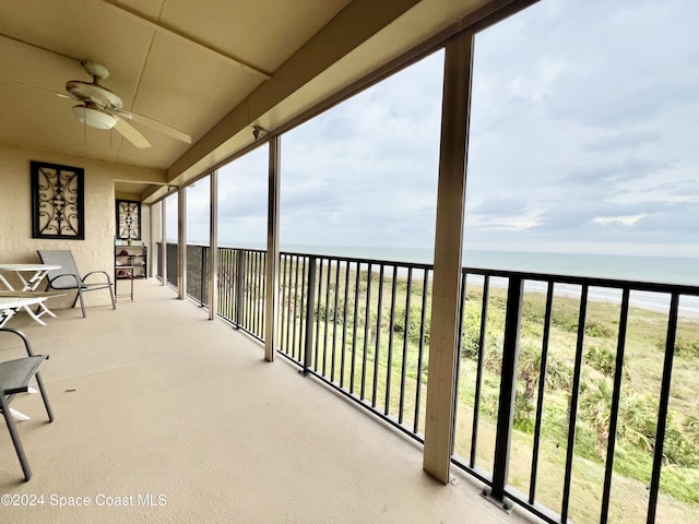 balcony featuring ceiling fan, a water view, and a beach view