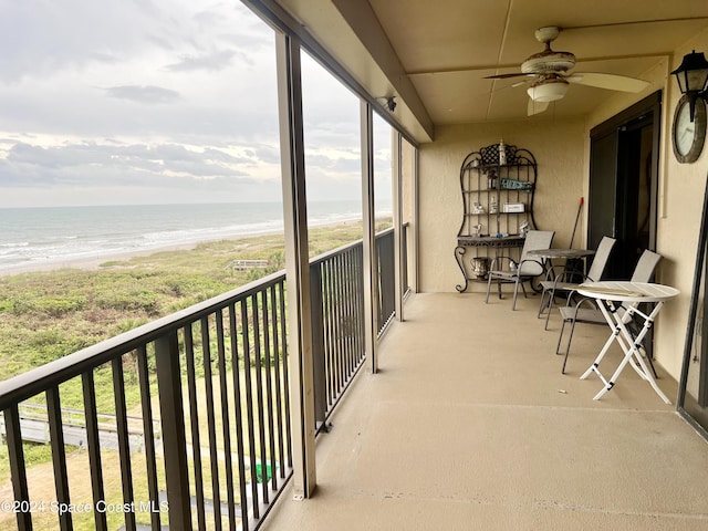 balcony with a beach view, a water view, and ceiling fan