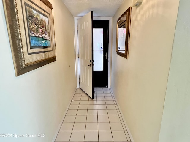 hallway featuring light tile patterned floors and a textured ceiling